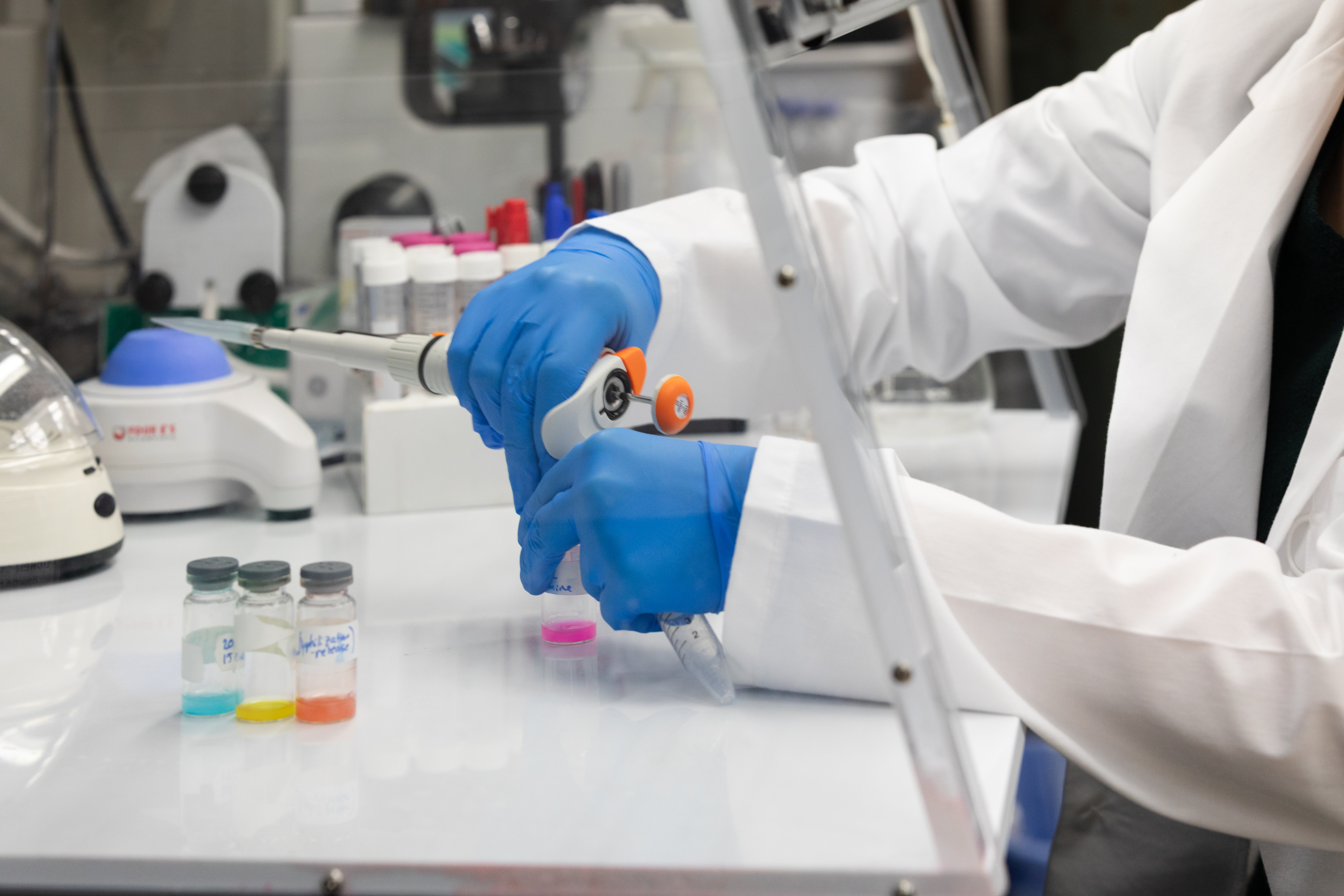 Students examining a beaker filled with green liquid in a laboratory setting.