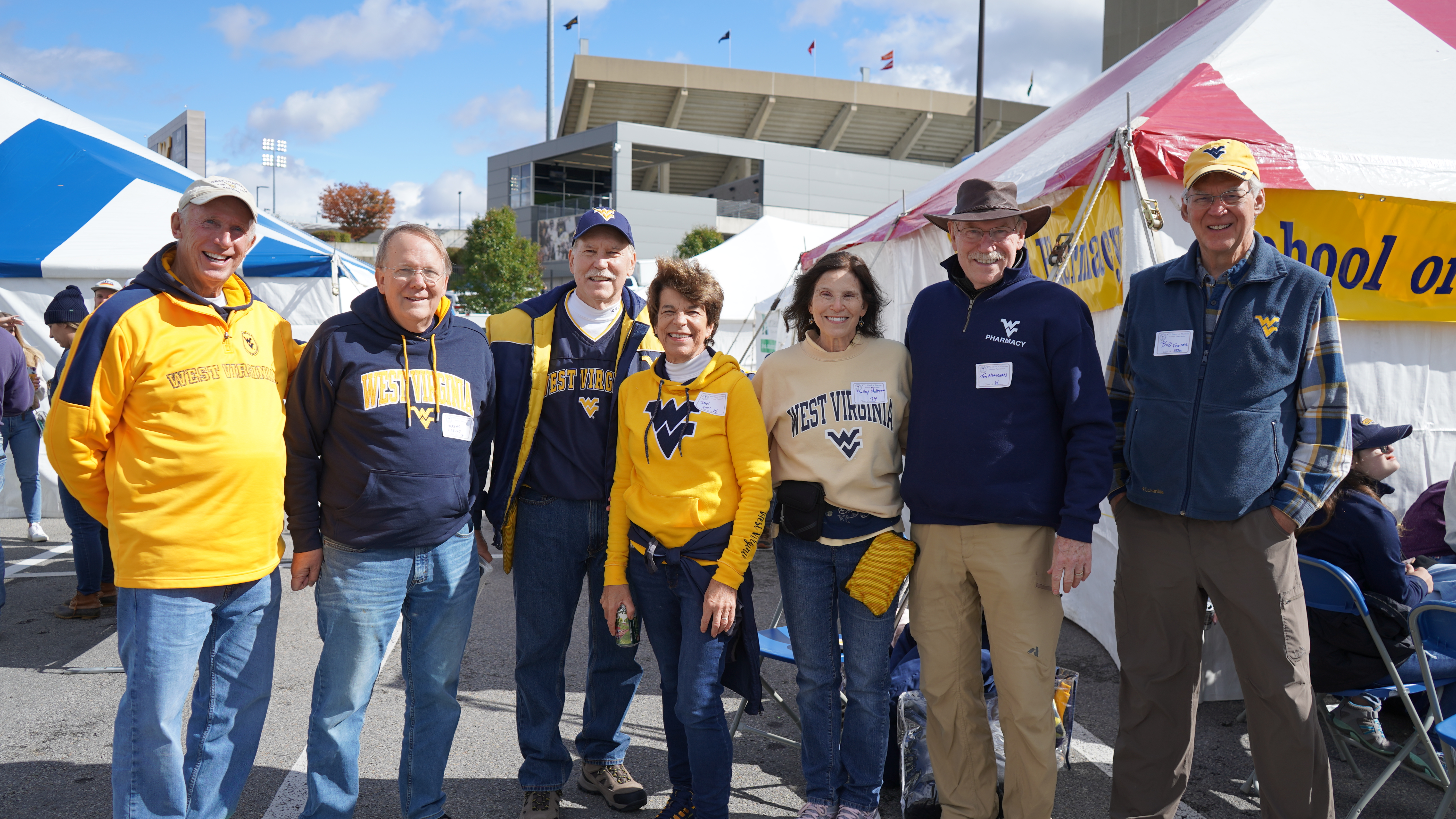 A group of seven alumni at the 2023 Homecoming tailgate tent.