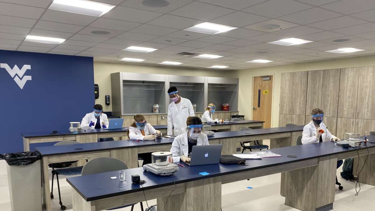 Pharmacy students make capsules in a lab class.