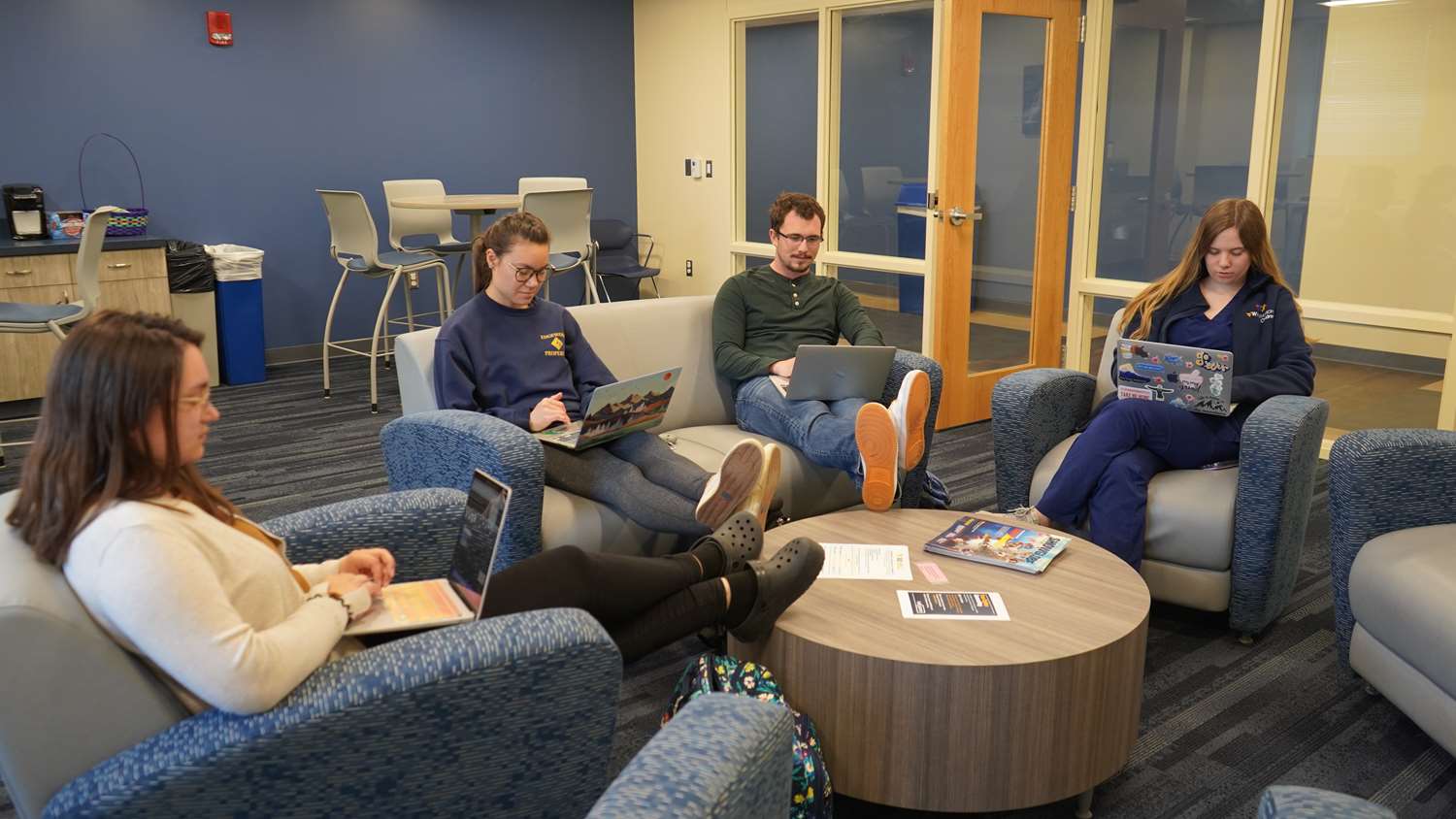 Four students sitting in a circle reading.